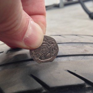 Place the coin in the groves of the tyre.